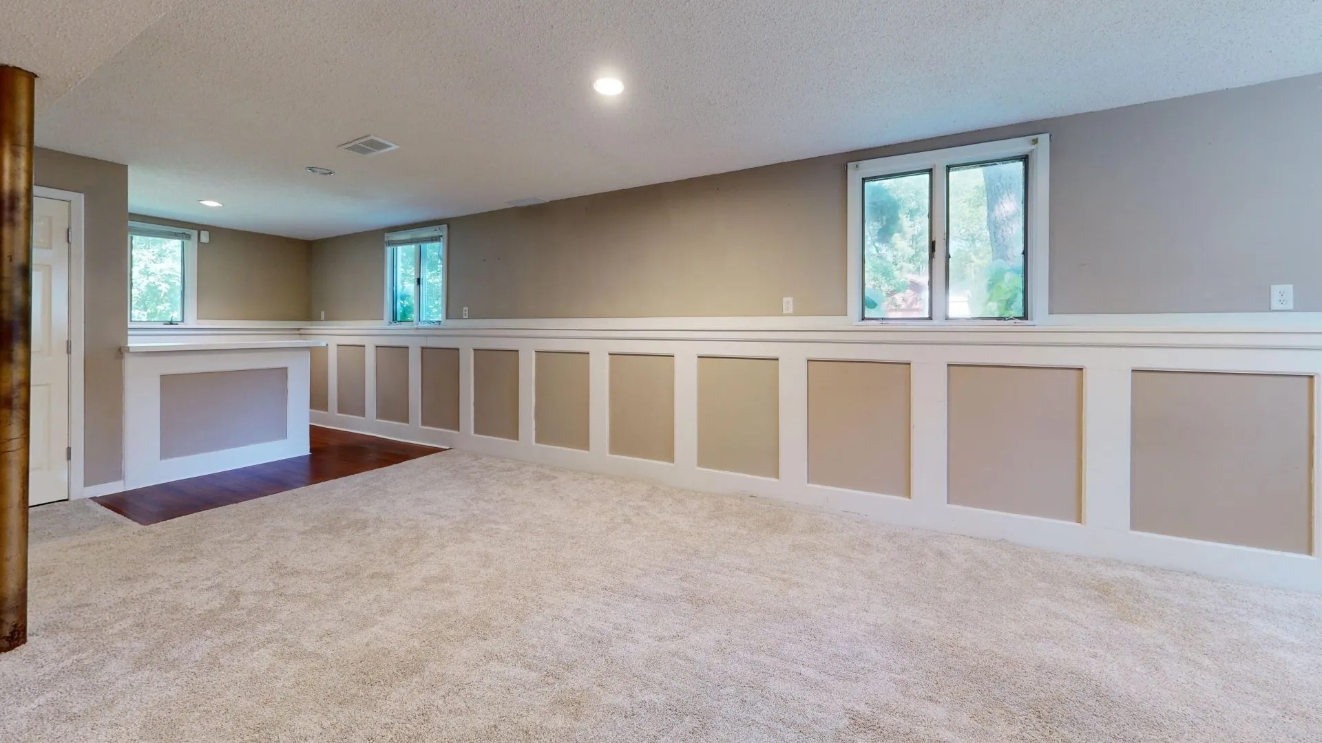 Bright renovated basement with wainscoting and recessed lighting