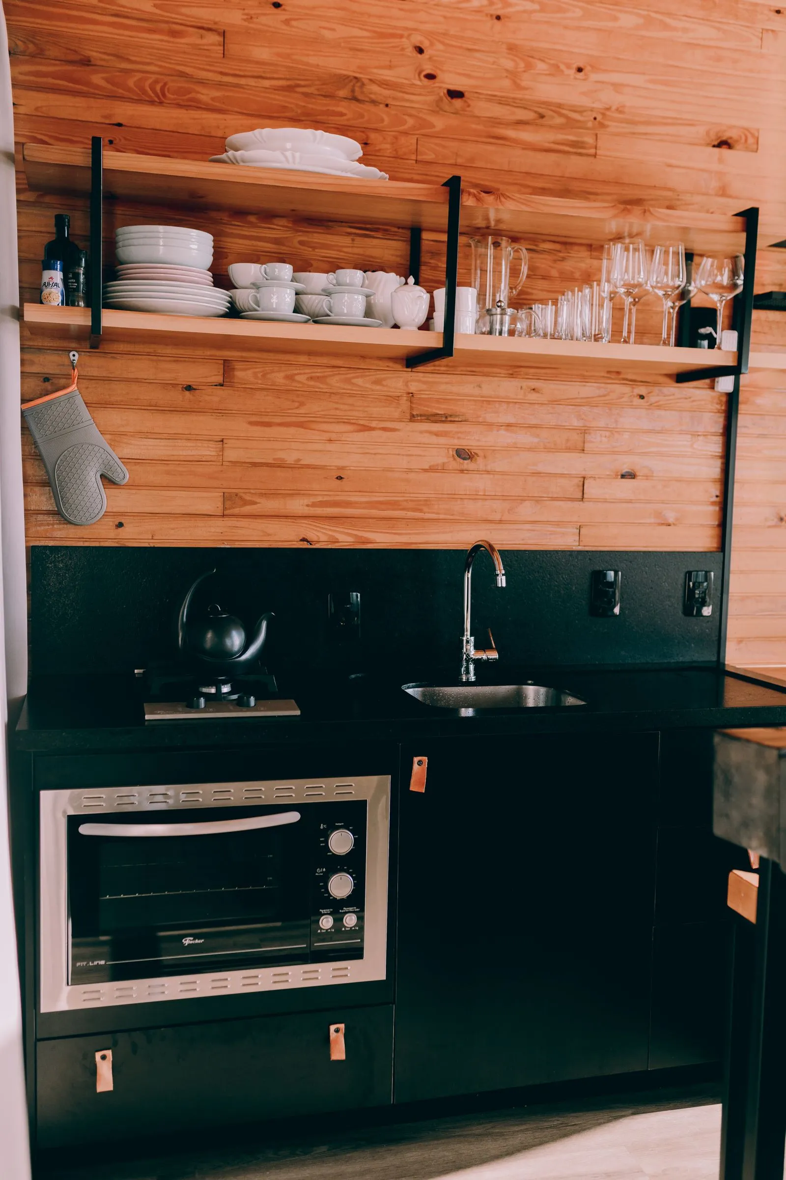Kitchenette with black cabinets, wood shelves and sink